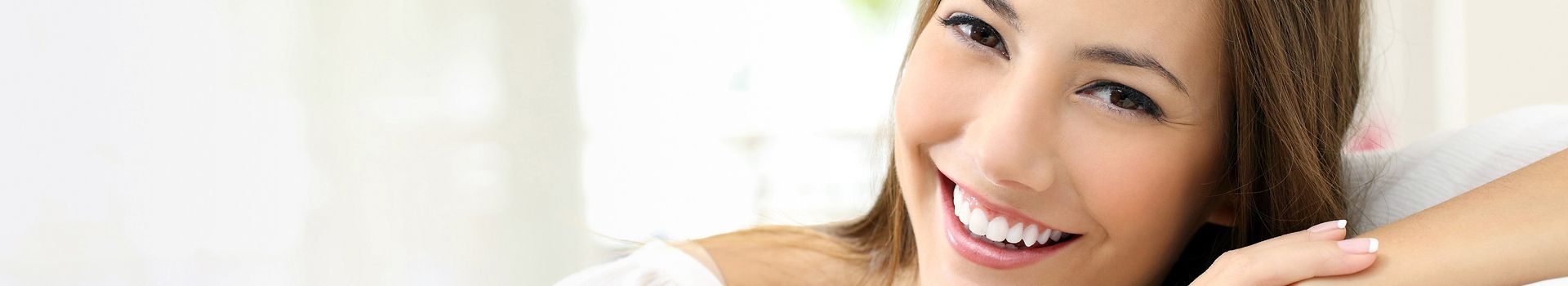 Eine lächelnde Frau sitzt entspannt auf einem Sofa.