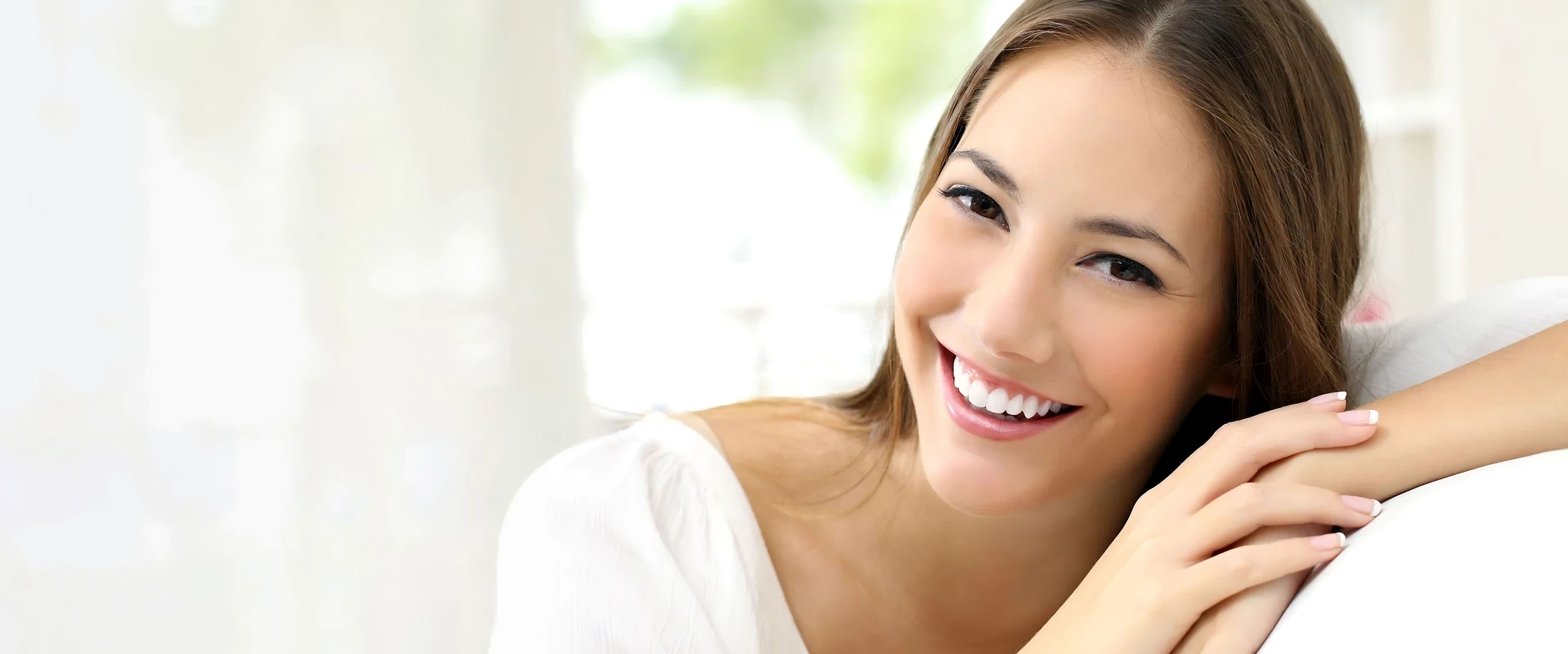 Eine lächelnde Frau sitzt entspannt auf einem Sofa.